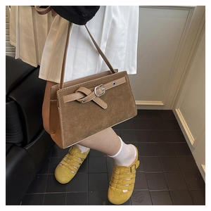 Détail d'un sac à bandoulière marron vintage avec texture en daim et boucle décorative