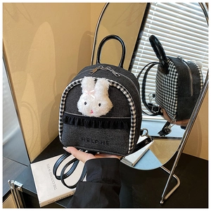 Close-up of denim backpack featuring plush rabbit decor and black-white checkered side