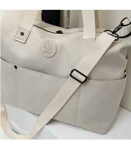 Close-up of cream canvas fitness bag featuring adjustable strap and embossed logo detail