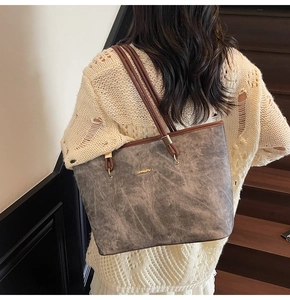 Detail of grey tote bag with brown straps, gold hardware and textured matte finish