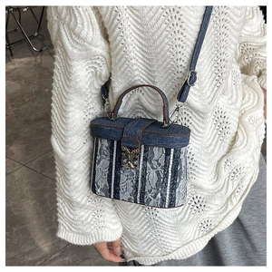 Detail of a vintage denim box bag with lace overlays and stripes on a model