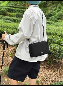 Outdoor crossbody bag in black nylon with adjustable woven strap and secure zipper compartments