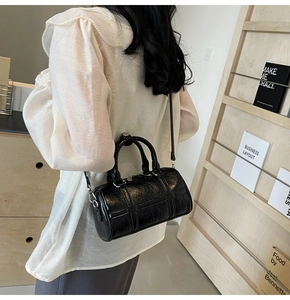 Détail de la texture cuir noir huilé sur un sac Boston tendance avec fermeture éclair argentée