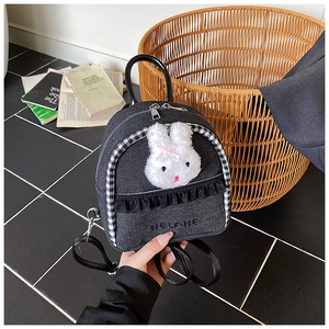 Detail showing denim backpack fabric with plush rabbit patch and black lace trim accents