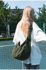 Detail of dark green nylon crescent bag with wide strap and matching mini pouch hanging
