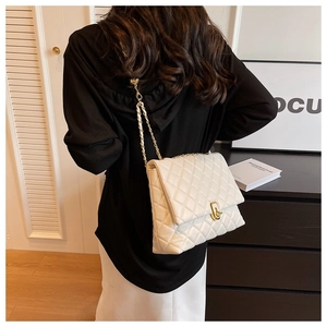 Close-up of a white quilted shoulder bag featuring a gold chain and metal twist lock