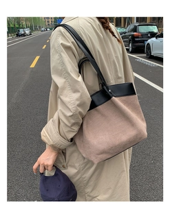 Brown suede tote bag with black leather trim shown on a model in an outdoor street setting