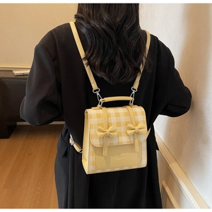 Dettaglio mini zaino a scacchi gialli e bianchi con fiocchi decorativi 3D e patta frontale