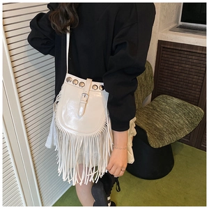 Detail of white saddle bag featuring silver rivets, leather strap buckle and long fringes