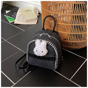 Detail of denim mini backpack with plush rabbit decor and black lace trim detail