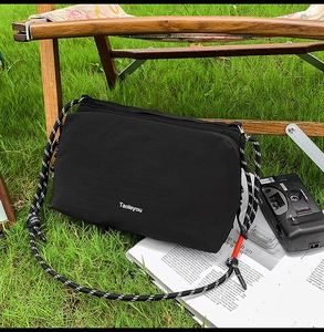 Close-up of black nylon crossbody bag with woven strap on a wooden chair outdoors