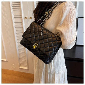 Detail of black quilted chain shoulder bag shown from a side view on a model