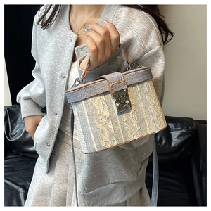 Detail view of the vintage denim and lace texture on a small box-shaped handbag