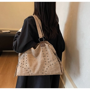 Detail of vintage beige tote bag featuring geometric metal rivet patterns and large metal rings