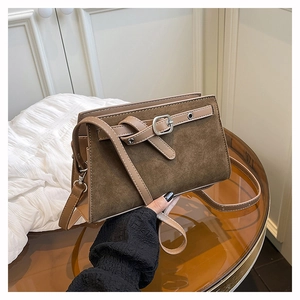 Détail de sac bandoulière rétro montrant le mélange de daim, cuir lisse et boucle décor