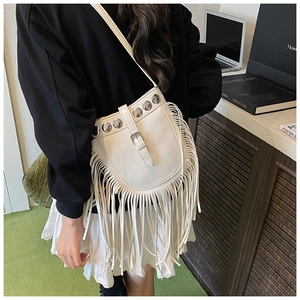 Close-up of white bucket bag with silver rivets and long tassels on a crossbody strap
