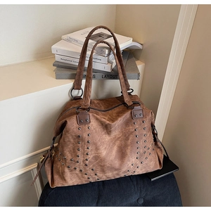 Close-up of vintage brown tote bag featuring metallic rivets and soft matte texture