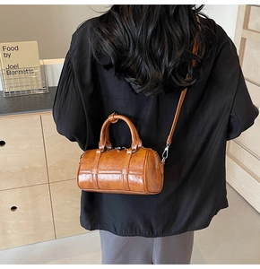 Sac boston en cuir marron porté par un mannequin dans un intérieur chic et épuré