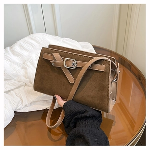 Détail du daim marron vintage et de la boucle argentée sur le petit sac carré à bandoulière