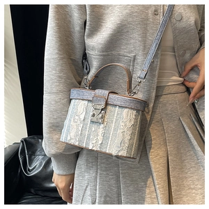 Light blue denim box bag with white lace overlay and brown leather handle on a model