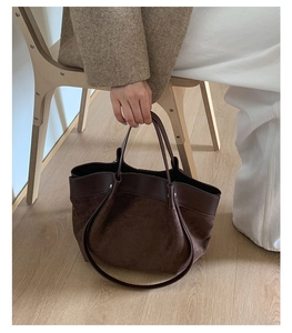 Brown suede tote bag with smooth leather handles shown in a lifestyle interior setting