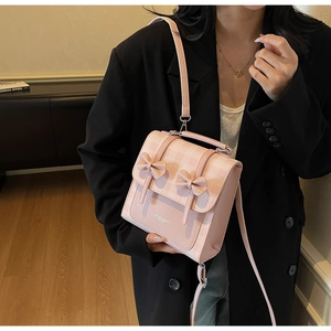 Dettaglio di una borsa a quadri rosa con fiocchi, indossata da una modella in abito nero