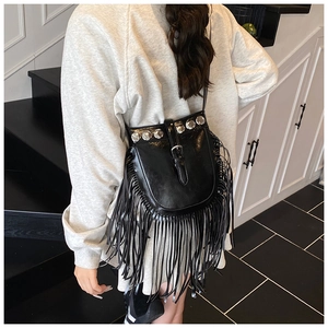 Detail of black crossbody bucket bag with silver studs and long bohemian fringe