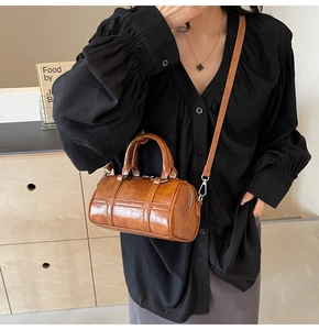Détail d'un sac cylindre en cuir marron avec poignées et bandoulière réglable