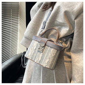 Close-up of a blue box bucket bag with white floral lace and brown leather trim