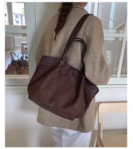 Detail of a large brown suede tote bag worn on shoulder showing texture and capacity
