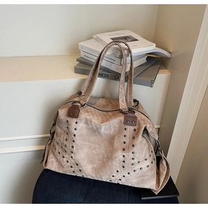 Close-up of vintage brown tote bag with metal rivet studs and detachable shoulder strap