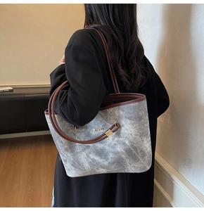 Detail of grey textured tote bag featuring leather straps and metal JINGPIN logo