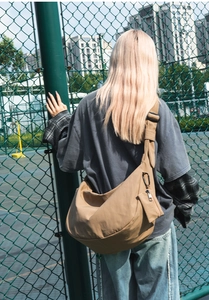 Outdoor shot of large khaki nylon hobo bag with wide strap and matching mini pouch