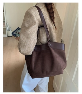 Detailed close-up of dark brown suede and leather splicing tote bag carried by a model