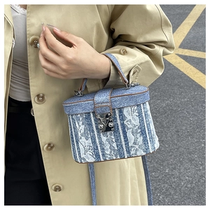 Detail of vintage denim bucket bag featuring white lace patchwork and brown leather trim
