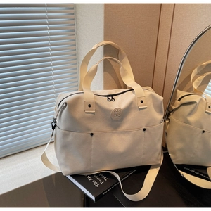 Detail of cream canvas duffel bag with black handles and round logo on books