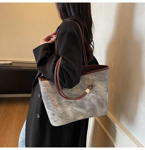 Close-up of a marbled grey tote bag with brown handles and a small gold logo