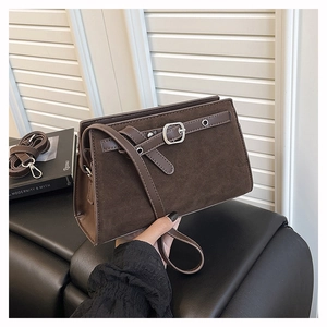 Détail d'un sac bandoulière marron rétro avec texture mate et sangle à boucle élégante