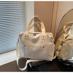 Detail of a beige waterproof gym bag with top handles, side pockets, and a round logo