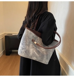Detail of large marble-pattern tote bag with brown leather handles and gold accents