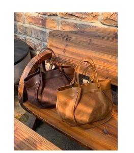 Detail of vintage contrast tote bag with matte suede and leather stitching on wooden bench