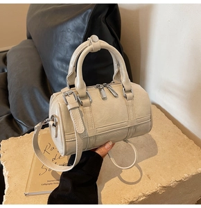 Détail macro du sac beige plissé avec texture en cuir et boucles métalliques argentées