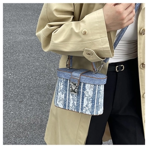 Detail of blue denim and lace box bag with brown leather trim and silver metal lock