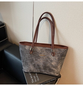 Detail of grey textured tote bag with brown leather handles and golden JINGPIN logo