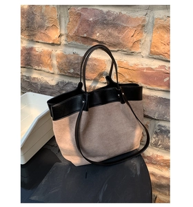 Detail of khaki suede tote bag with black leather handles and color-block stitching