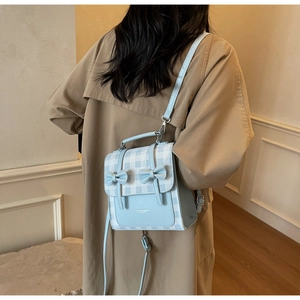 Borsa a tracolla a quadretti celeste con fiocchi indossata su un trench kaki raffinato