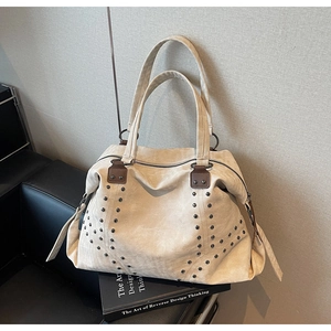 Detail of beige suede tote bag with V-shaped metal studs and dark brown leather handles