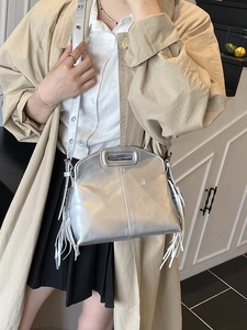 Silver metallic tassel bucket bag with hollow handles shown on model in street style