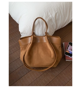 Detail of camel tote bag with contrast leather stitching on dark wood floor