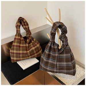 Detail view of plaid tote bags with unique knot handles in red and blue tartan patterns